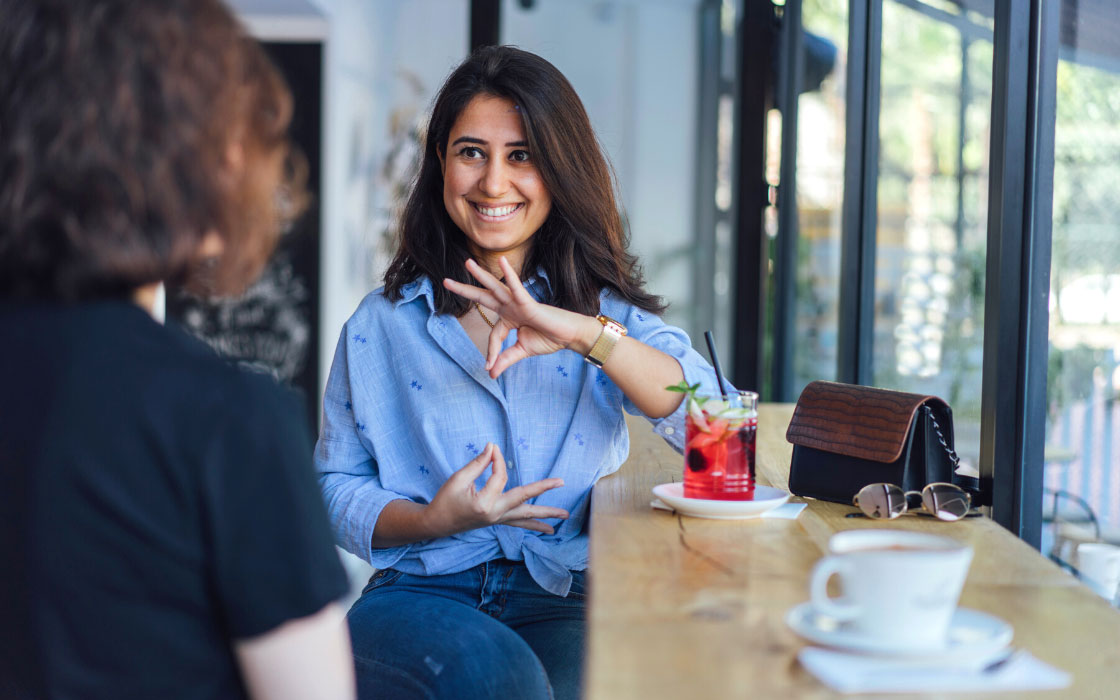 Zwei Frauen im Café, von der eine gerade die Gebärdensprache nutzt