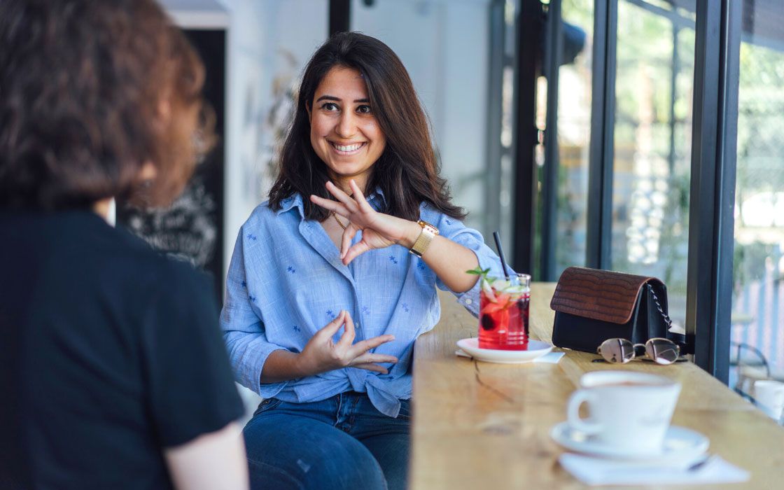 Eine Frau gebärdendolmetscht in einem Café