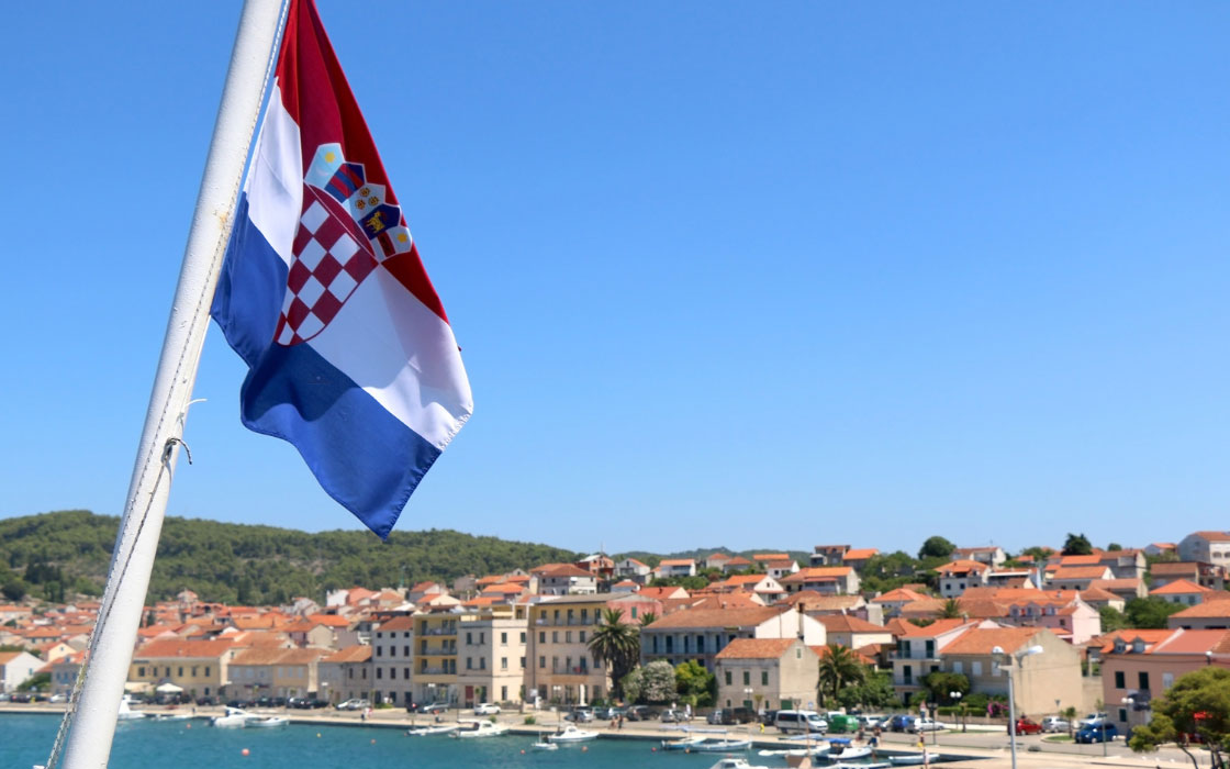 Kroatische Flagge weht im Vordergrund. Im Hintergrund der Blick auf die Insel Korcula.