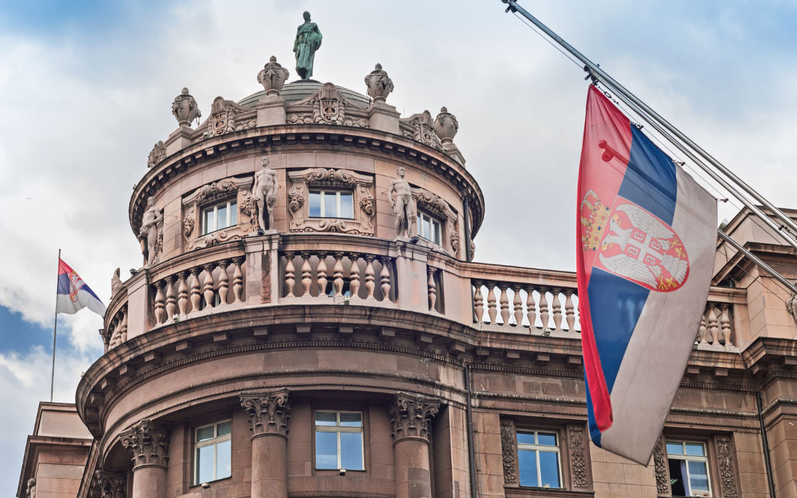 Serbische Flagge vor einem serbischen Regierungsgebäude.