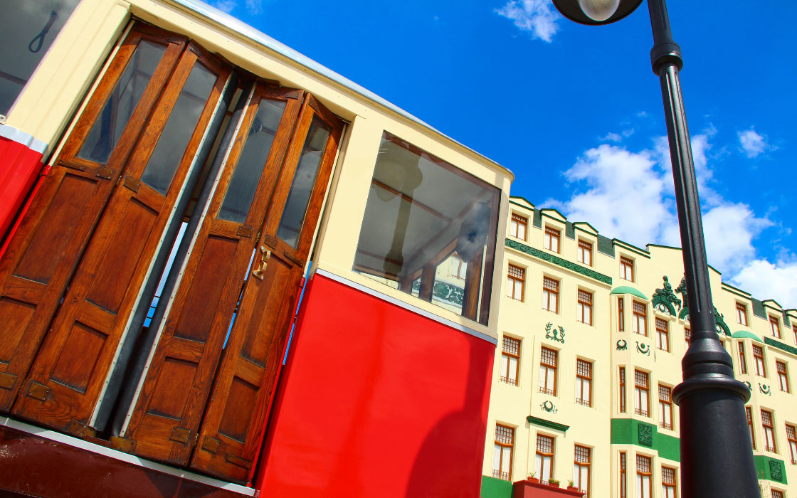 Ausschnitt einer Straßenbahn. Dahinter ein Gebäude.